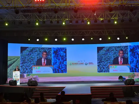Siraj Hussain speaking at the podium, shown on large screens, at the Wheat Summit 2025